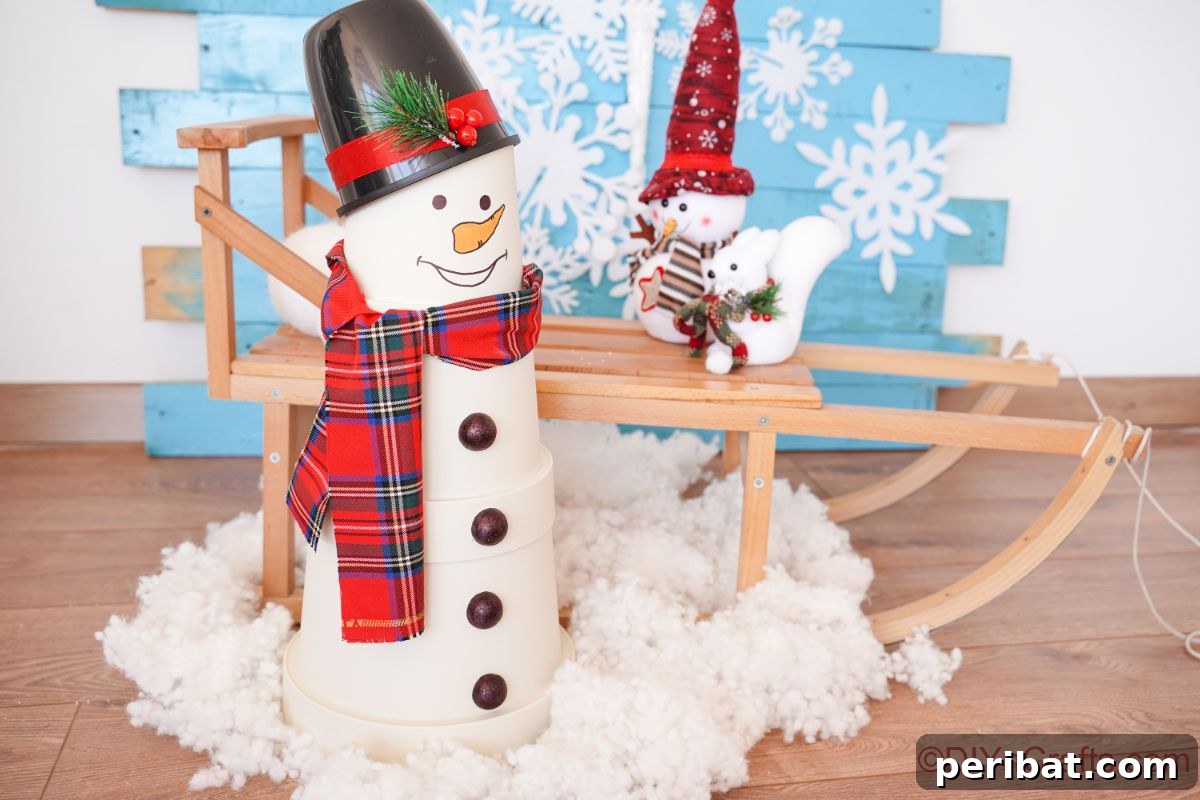 A charming flower pot snowman set on artificial snow, with a rustic wooden sleigh in the background