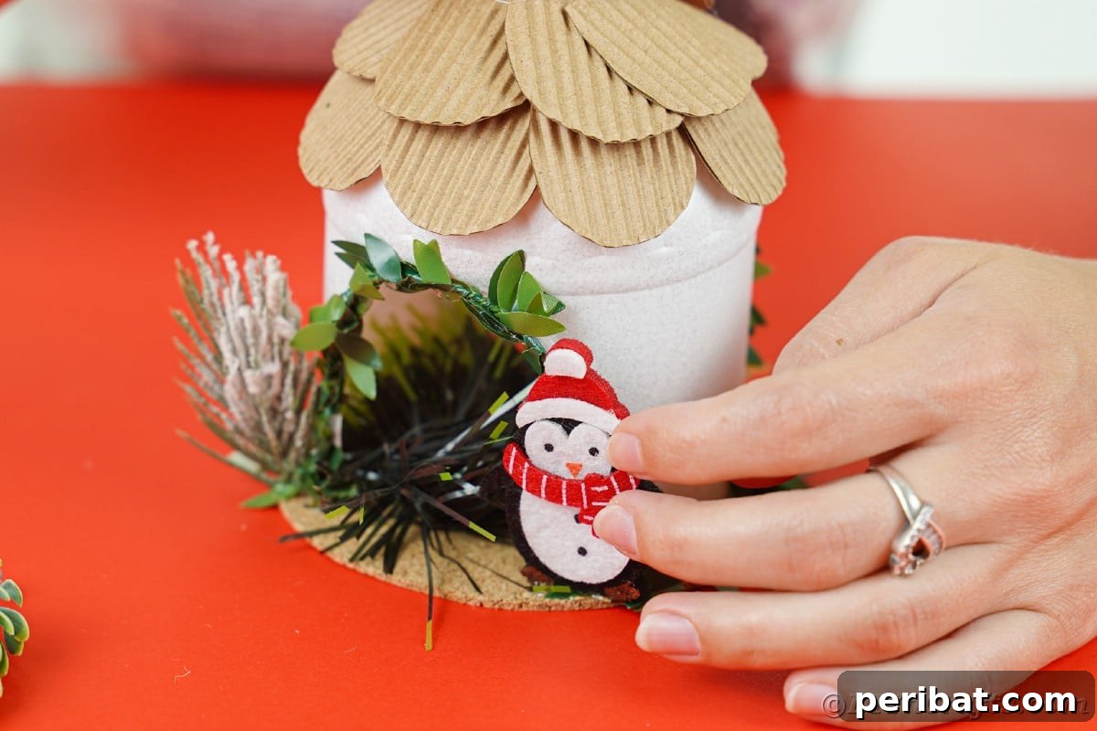 Arctic Home Crafted from Upcycled Plastic 20 Ladies hand putting fake penguin on side of white rounded mini house