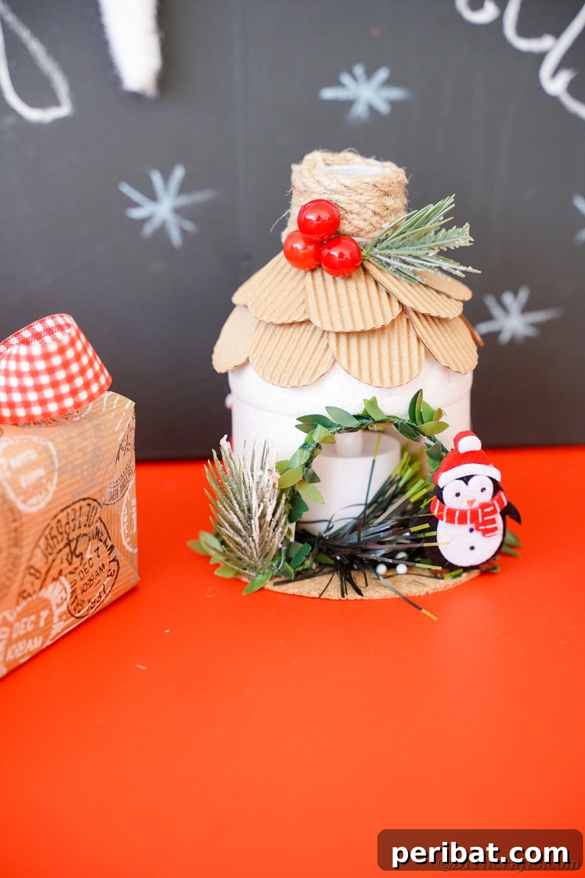 Arctic Home Crafted from Upcycled Plastic 31 white lantern in house shape with cardboard shingles on red table by chalkboard
