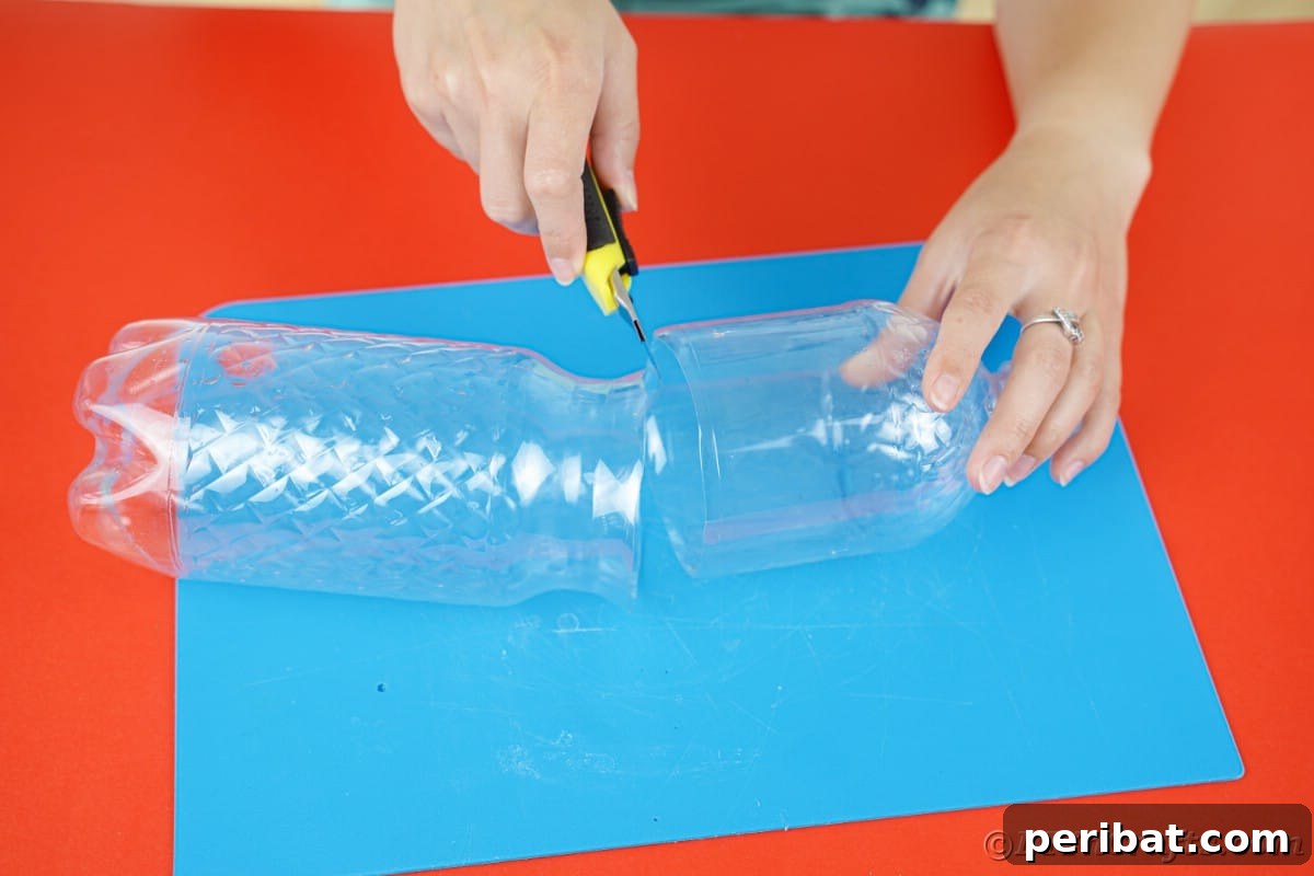 black and yellow craft knife being used by hands to cut empty plastic bottle in half
