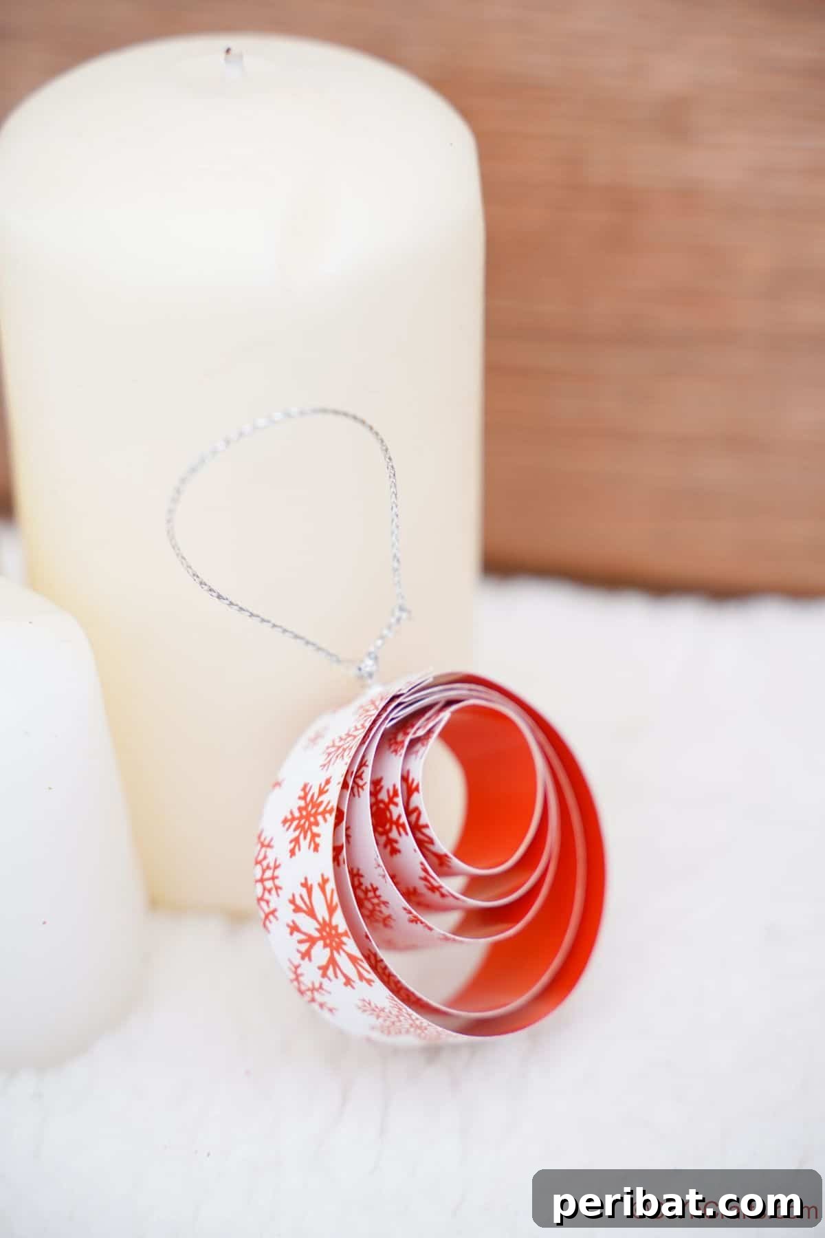 Layered Rolled Paper Christmas Charm 6 round paper red and white ornament leaning against white candle