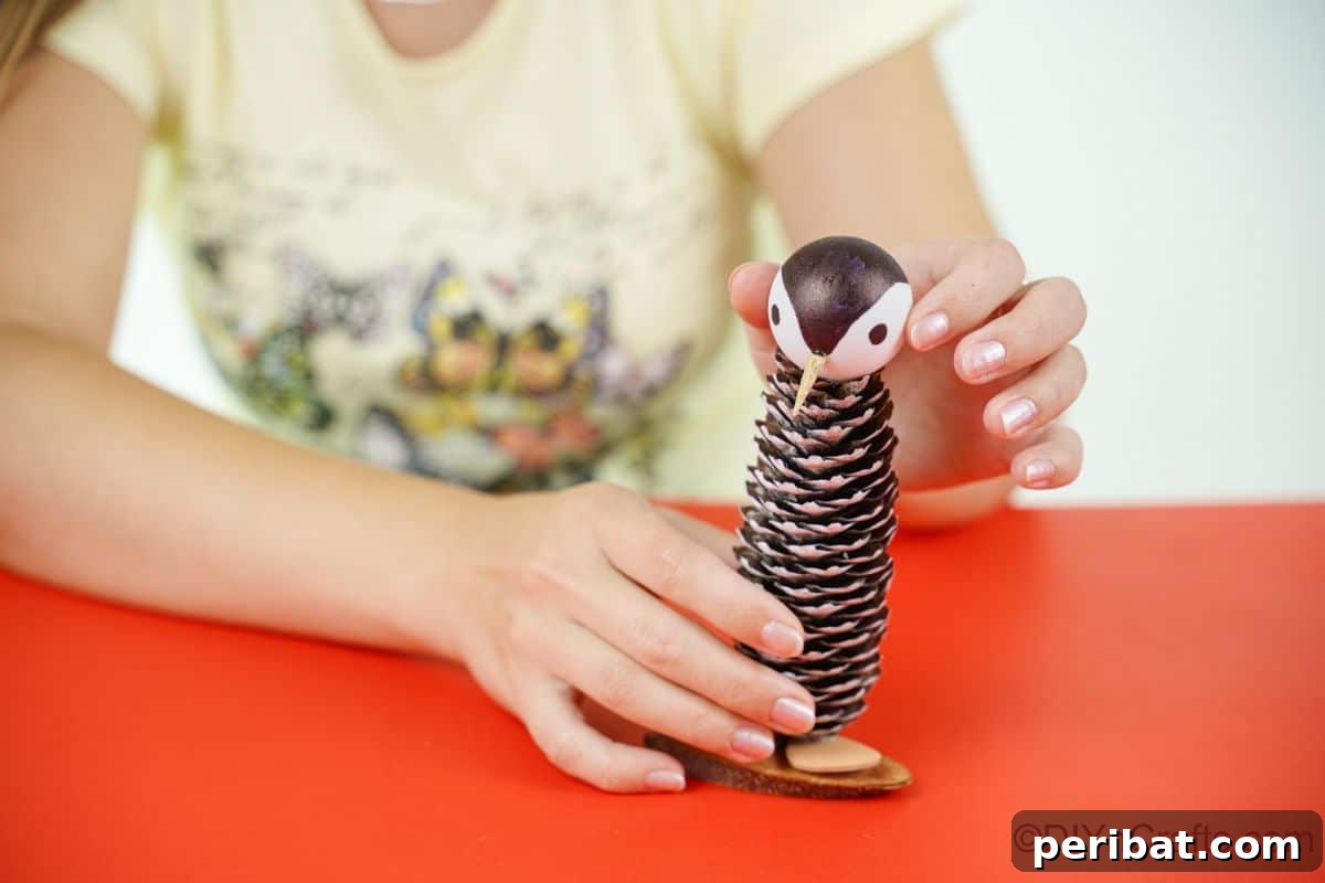 Winter Pinecone Penguin Fun 22 hand holding penguin face on top of pinecone