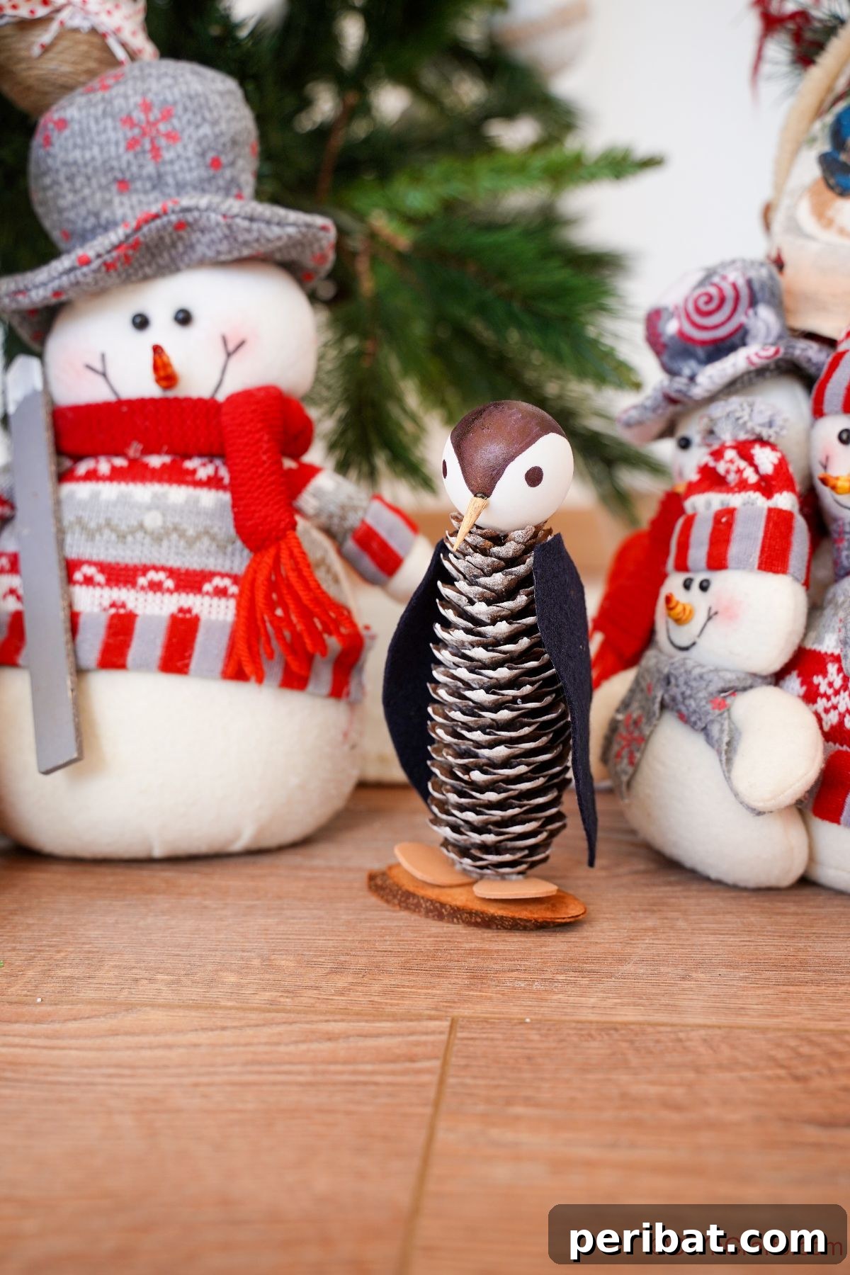 Winter Pinecone Penguin Fun 26 A completed pinecone penguin perched on a rustic wood table, with a charming fake snowman in the soft-focus background, creating a serene winter scene.