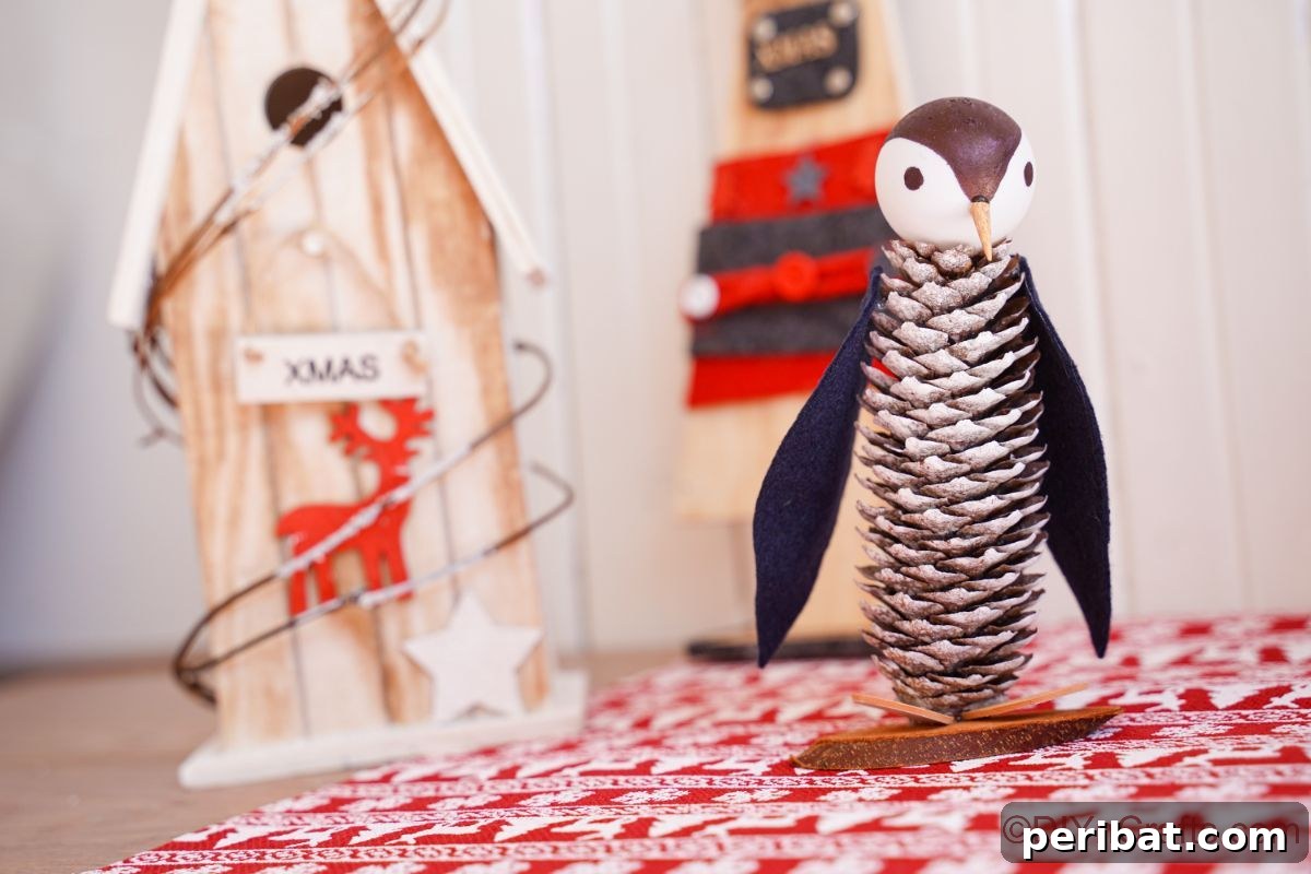 Winter Pinecone Penguin Fun 8 A cute miniature pinecone penguin sitting on festive red and white striped paper, ready for a winter celebration.