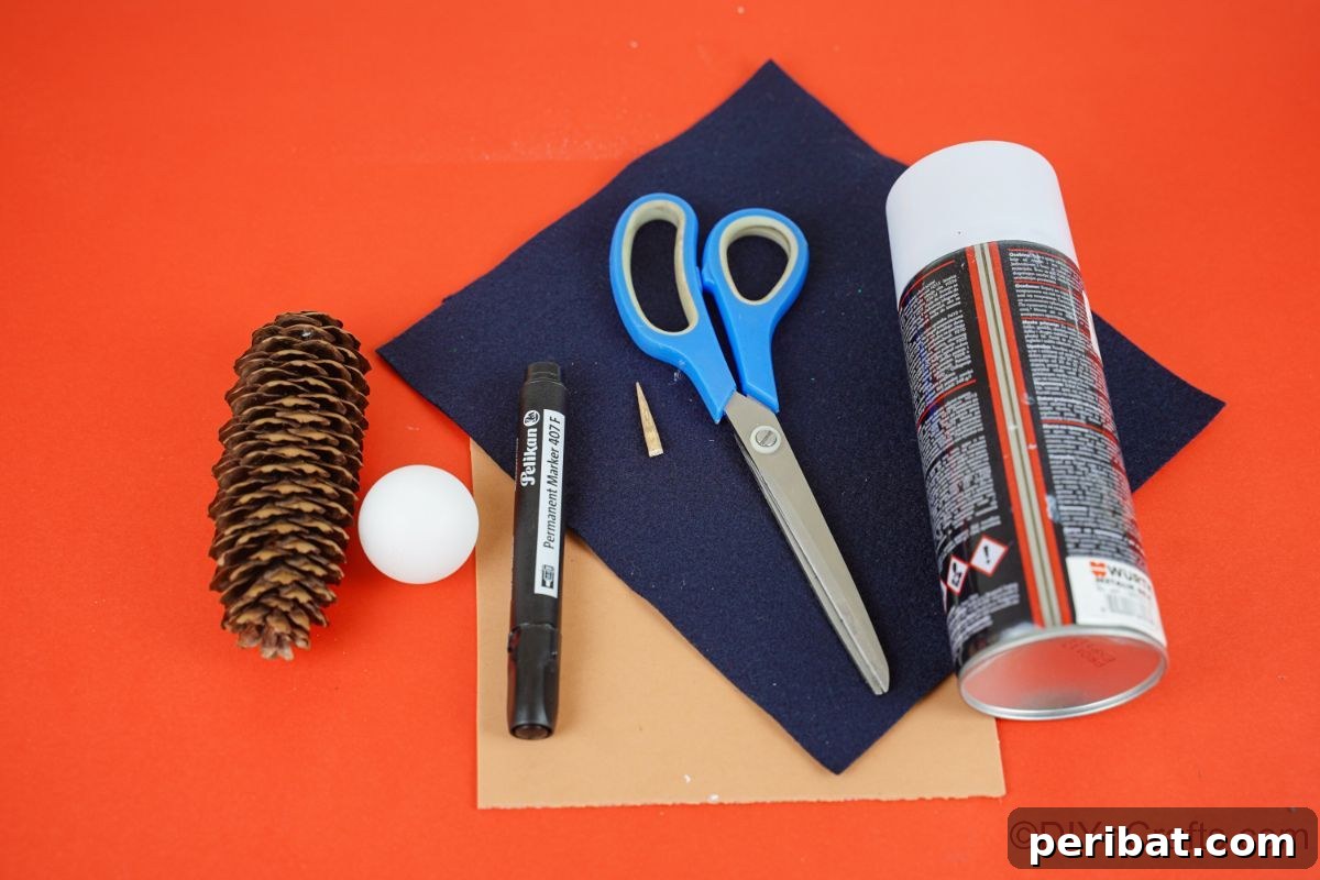 Winter Pinecone Penguin Fun 10 Various craft supplies, including black and brown paper and a pinecone, neatly arranged on a red table, ready for crafting.