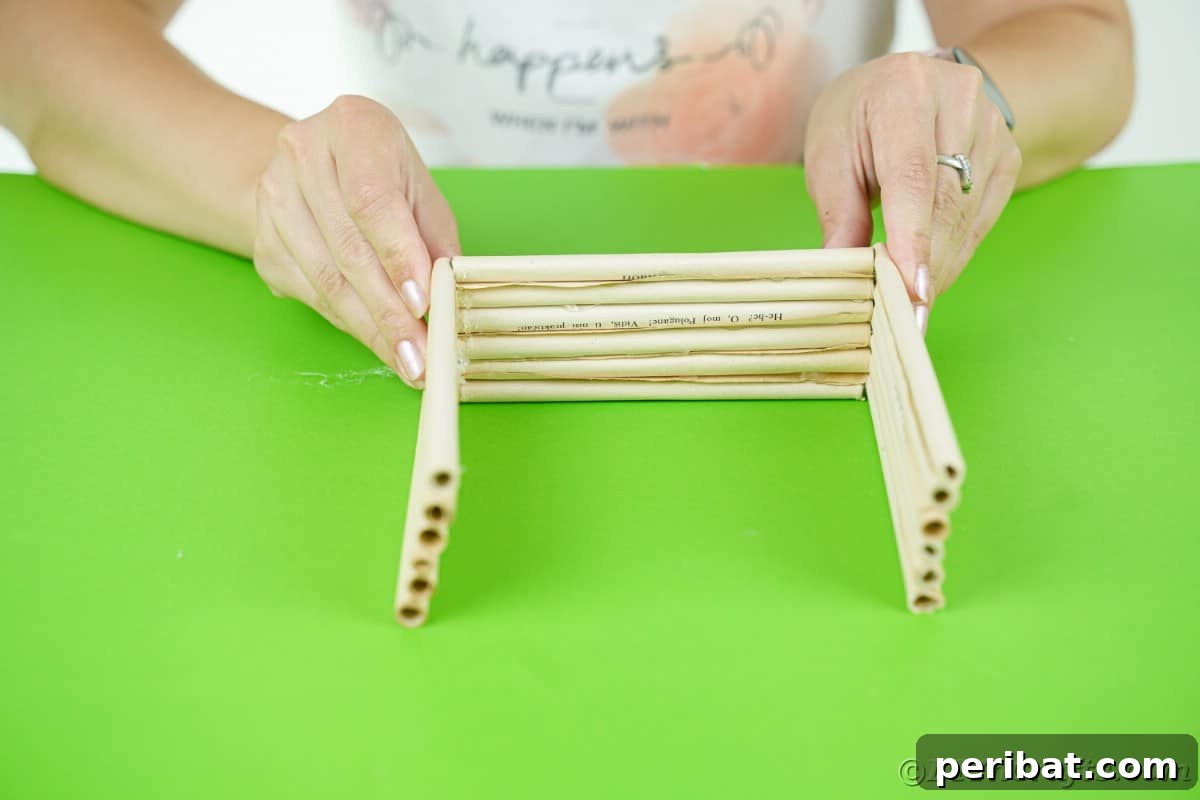 hands holding paper log walls together for workshop on green table