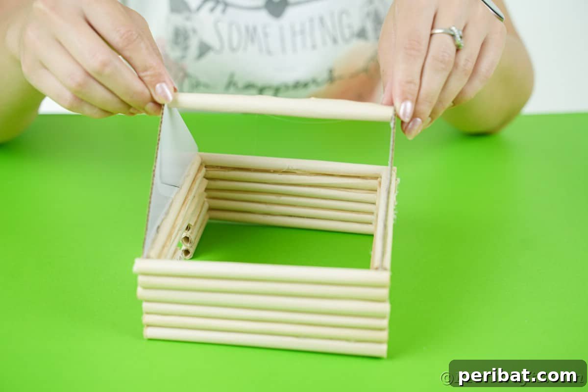 adding a log to the top of the miniature cabin to hold ends together