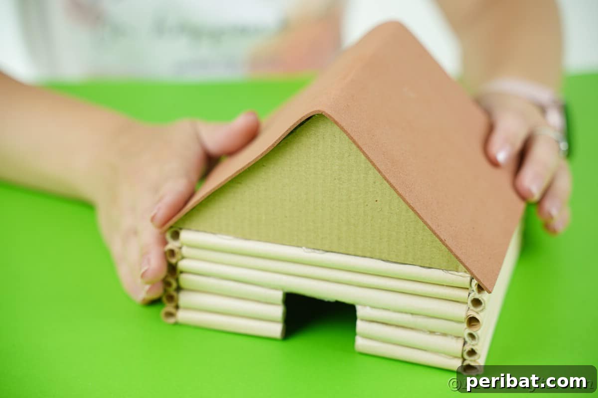 hands holding brown paper over top of miniature cabin