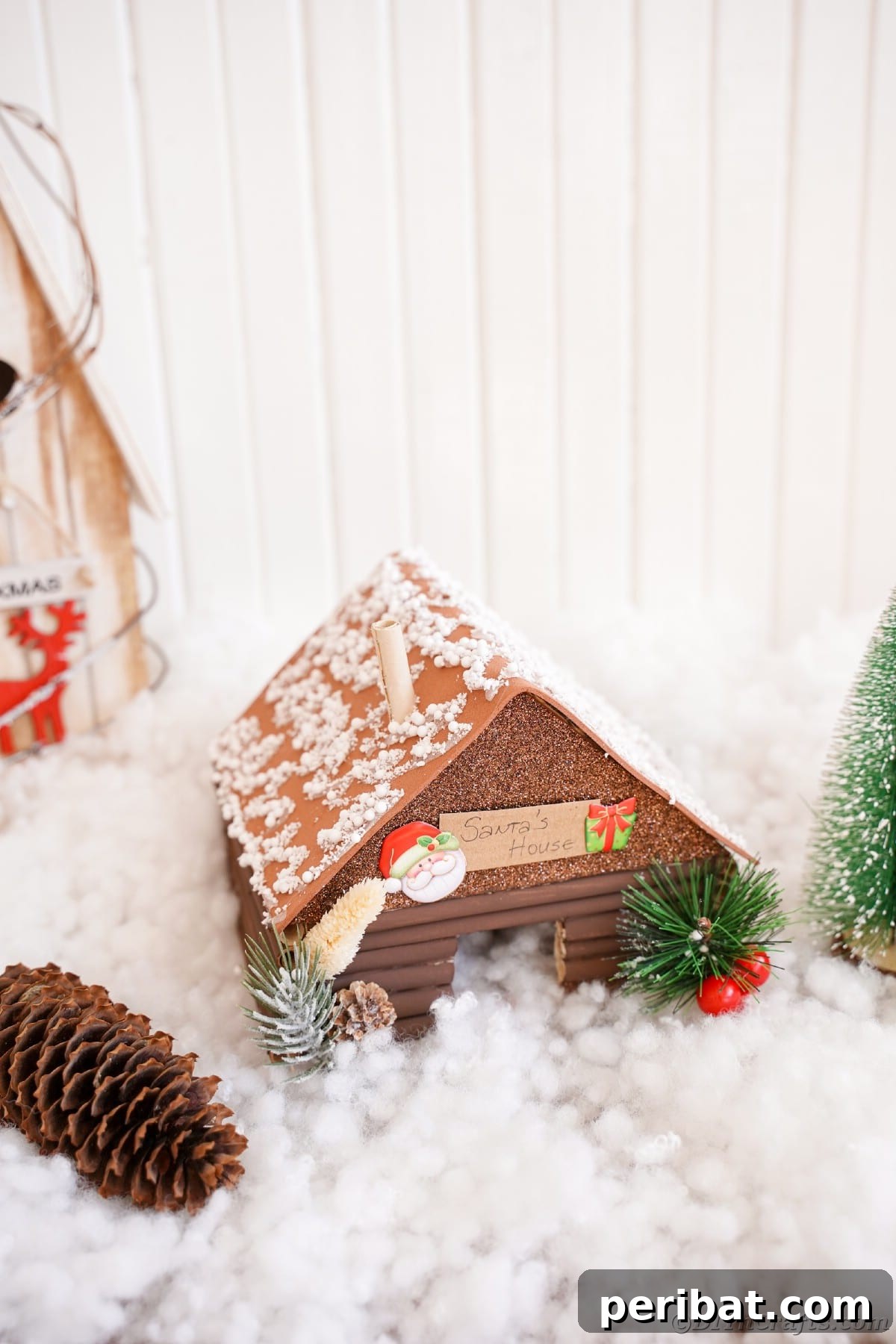 mini santa workshop on fake snow in front of white shiplap wall