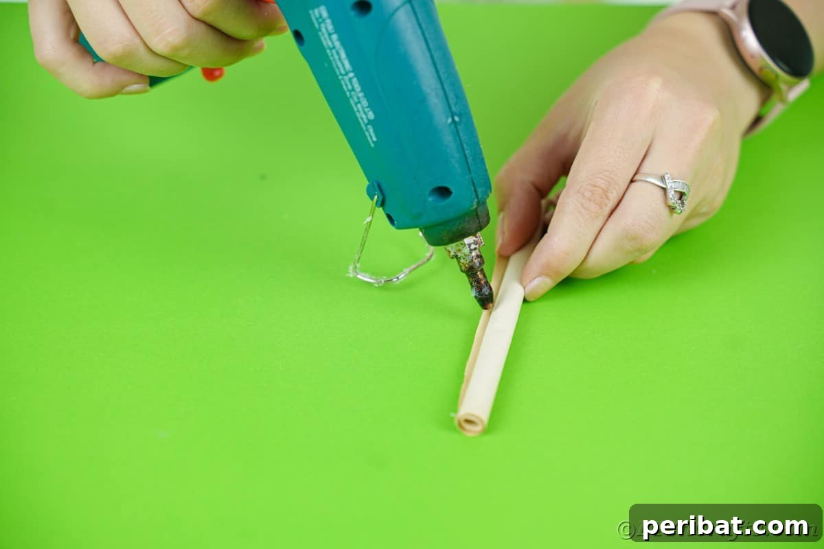 hand holding blue glue gun and adding glue on roll of paper