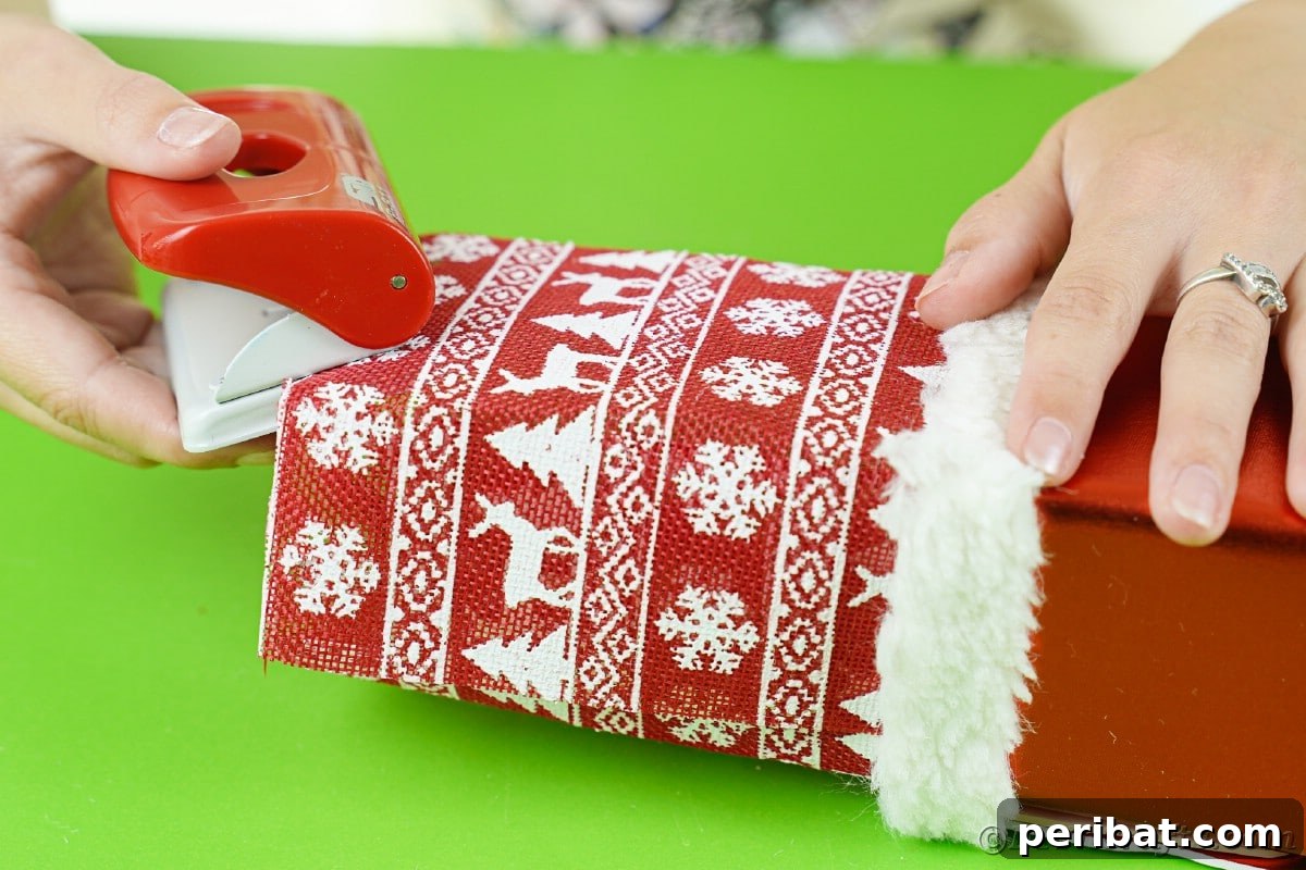 Jolly Upcycled Milk Carton Santa Candy Box 17 Red and gray hole punch making holes in the holiday paper hat on the box
