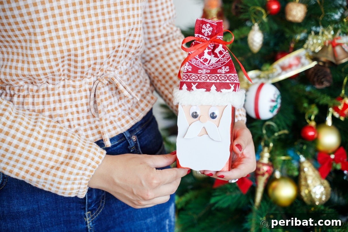 Jolly Upcycled Milk Carton Santa Candy Box 19 Woman holding a finished Santa box in front of a Christmas tree, ready for gifting or display