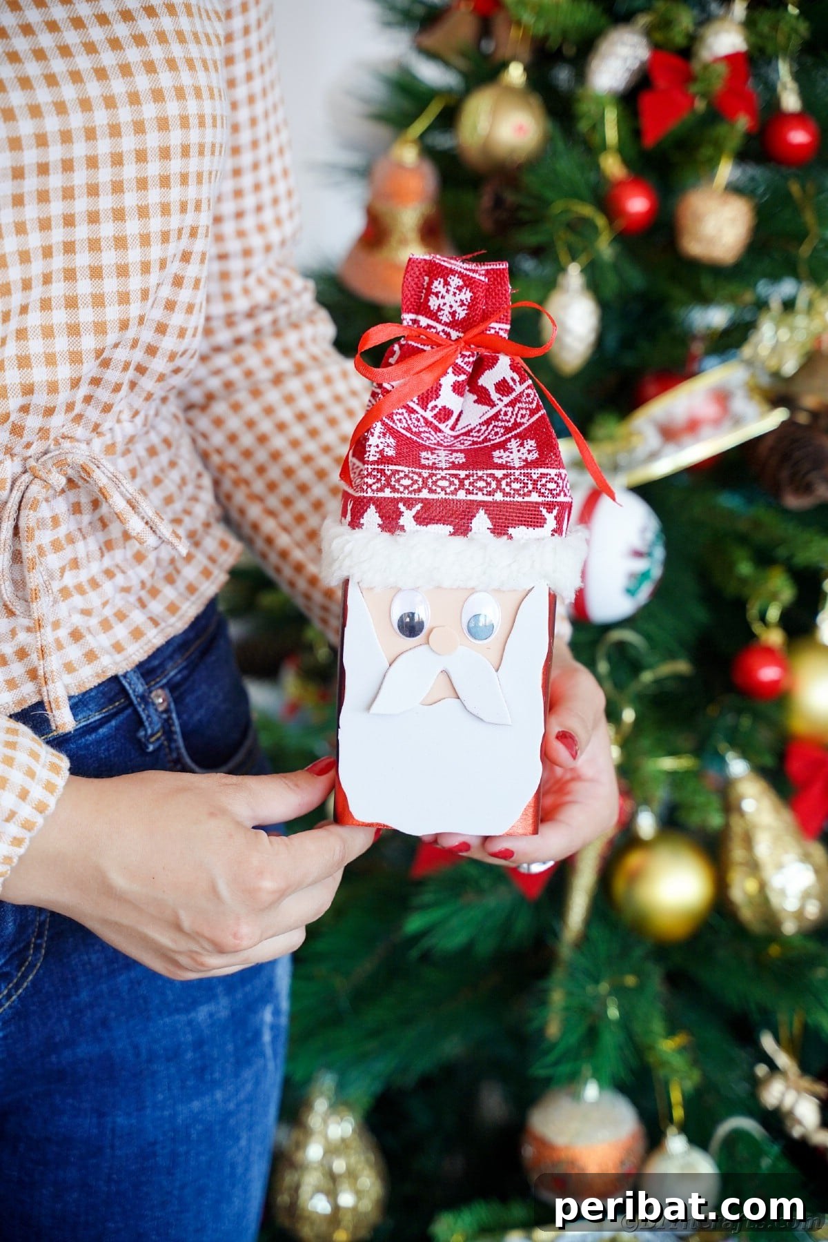 Jolly Upcycled Milk Carton Santa Candy Box 6 Woman in jeans and checked shirt holding a little Santa Claus box in front of a Christmas tree