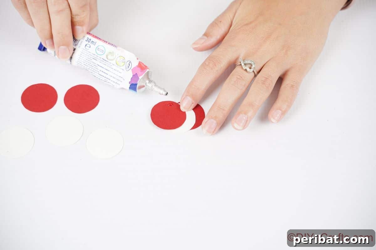 Sweet Peppermint Stick Decor 11 Hand gluing circles of red and white paper together, demonstrating the creation of the swirl design.
