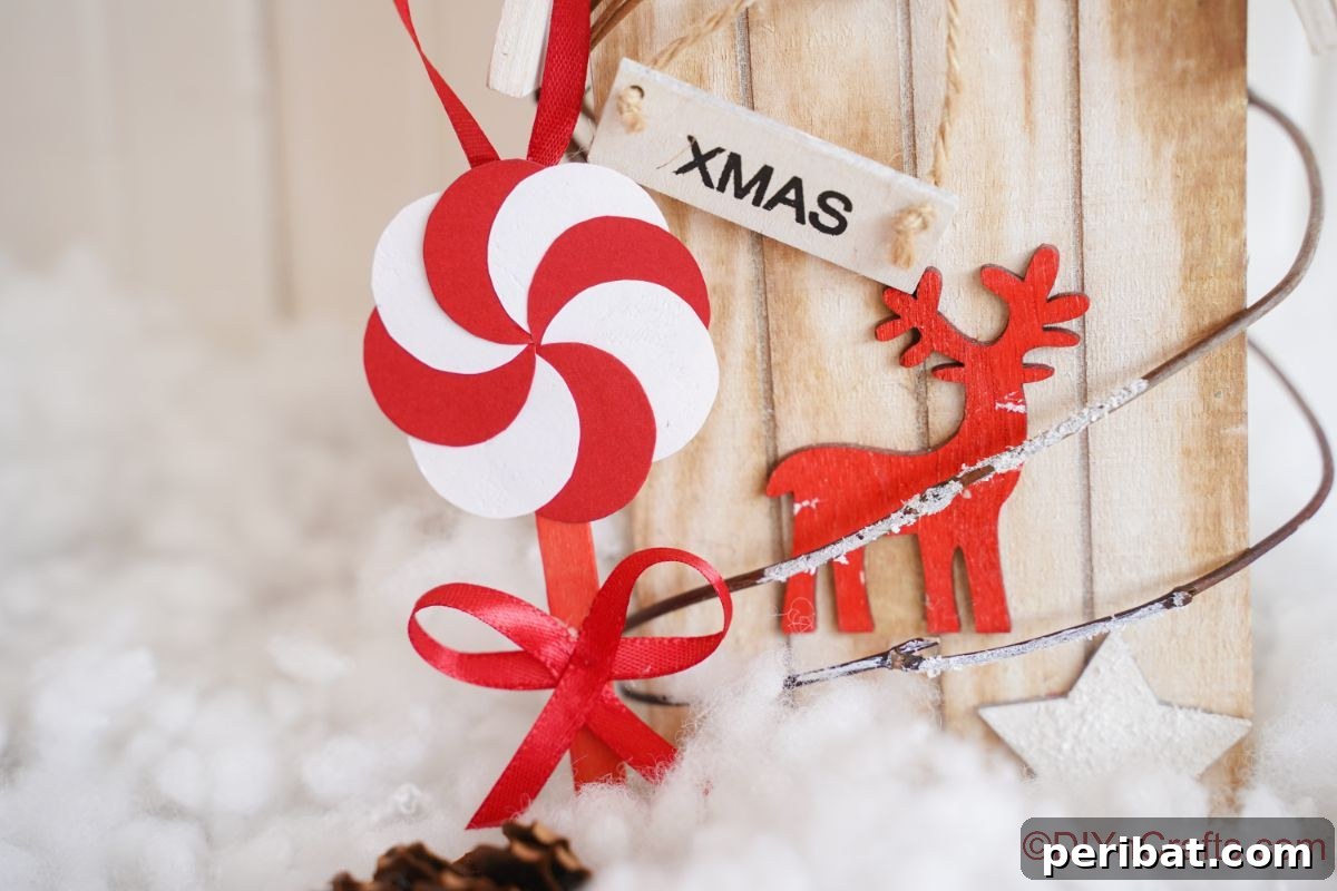 Sweet Peppermint Stick Decor 17 Fake peppermint candy ornament hanging on a holiday decoration with fake snow, highlighting creative display ideas.