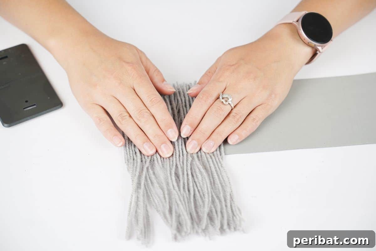 hand holding yarn down on gray paper
