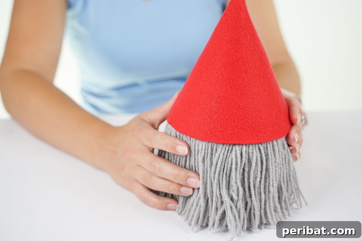 hands putting red hat on top of toilet paper roll gnome