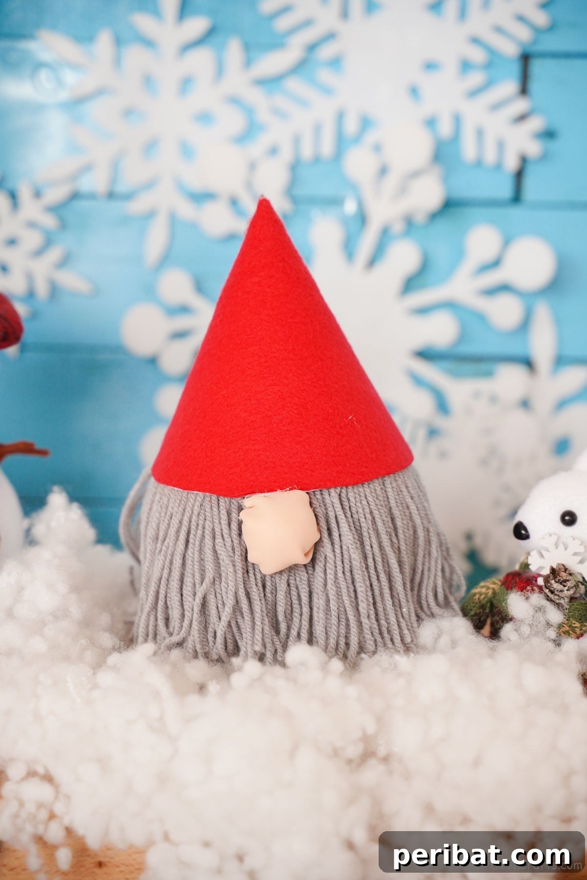 fake snow on table with blue background holding red hat gnome