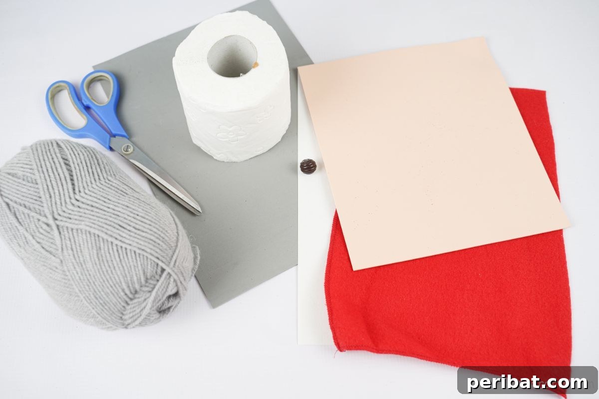 roll of toilet paper gray yarn red felt and gray foam paper on white table
