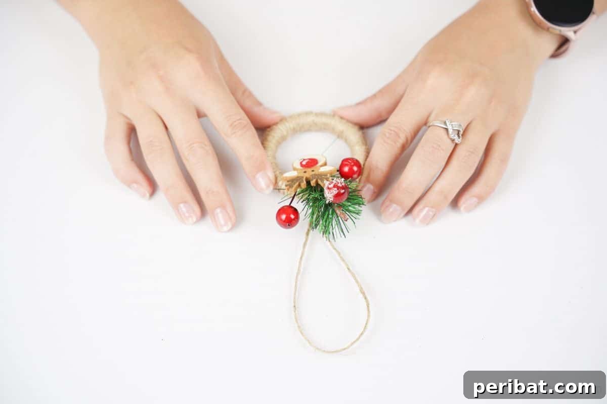Hands holding a beautifully completed mini wreath ornament, showcasing its rustic details and readiness for festive display.