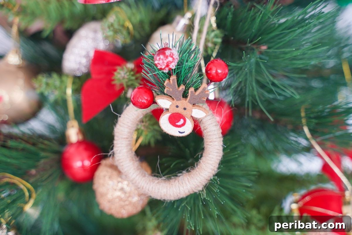 A charming miniature twine wreath ornament, adorned with a Rudolph figure and berries, hangs perfectly on a festive Christmas tree, ready for holiday celebrations.