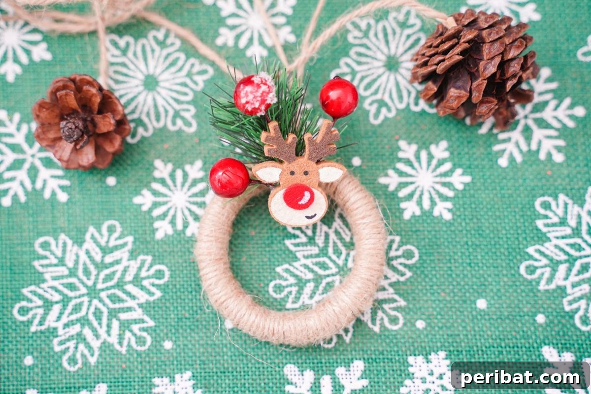 Miniature wreath ornament with rustic twine and delicate embellishments, presented on green and white snowflake patterned paper, highlighting its festive appeal.