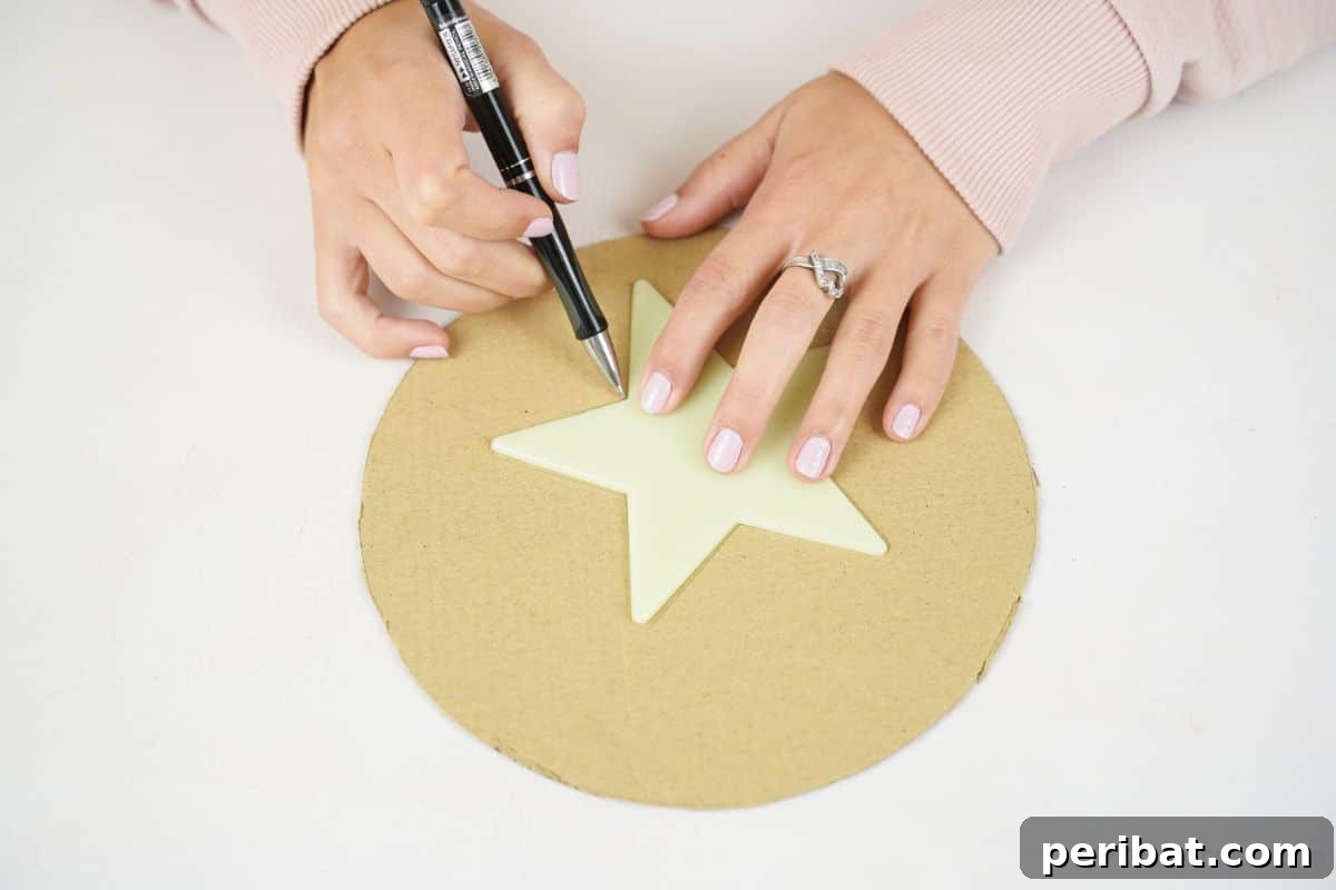 A hand carefully tracing a star shape onto a piece of cardboard, the first step in crafting.