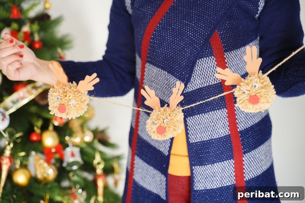 Festive Fluffy Reindeer Christmas Garland Craft 7 A person in a blue sweater holding a finished reindeer garland