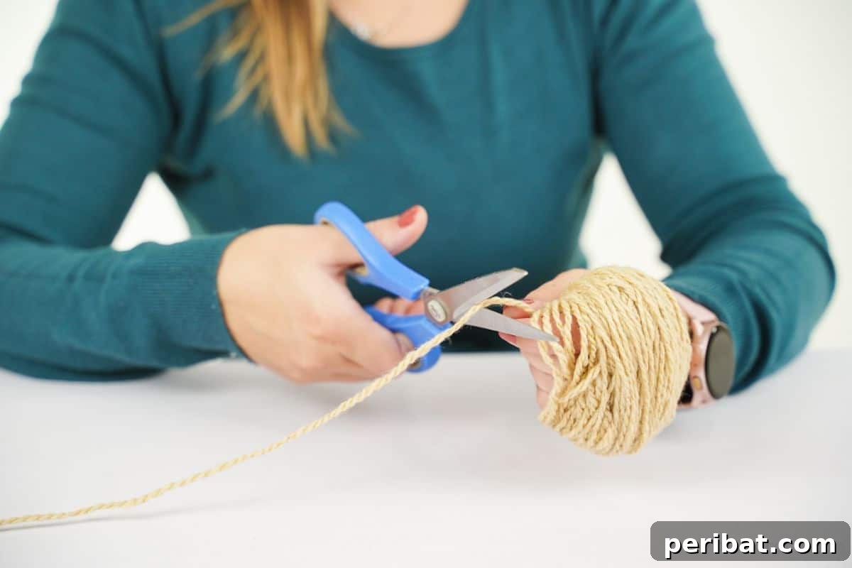 Festive Fluffy Reindeer Christmas Garland Craft 9 Woman cutting yarn with blue scissors to prepare for making a pom pom