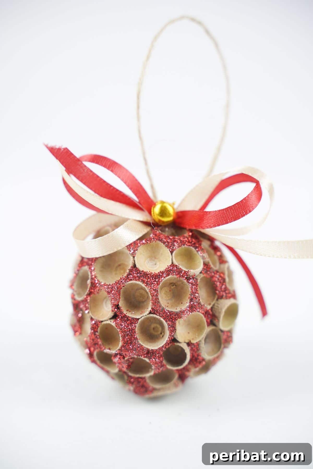 Handcrafted Sparkling Acorn Cap Christmas Ornament 22 A finished acorn cap glitter ornament with a pink glow, displayed prominently on a clean white table, highlighting its intricate details.