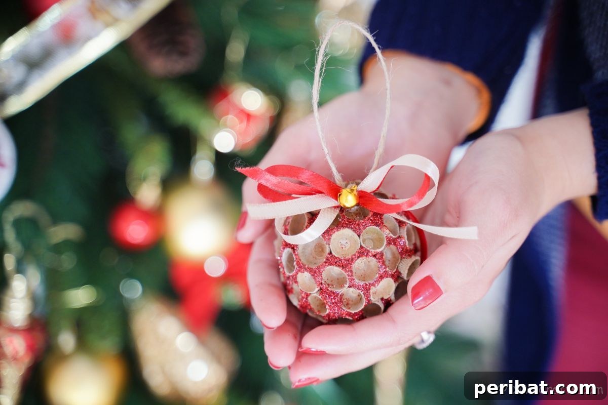 Handcrafted Sparkling Acorn Cap Christmas Ornament 23 A woman gently holding a shimmering acorn cap ornament, featuring sparkling glitter, in her hands, showcasing its delicate craftsmanship.