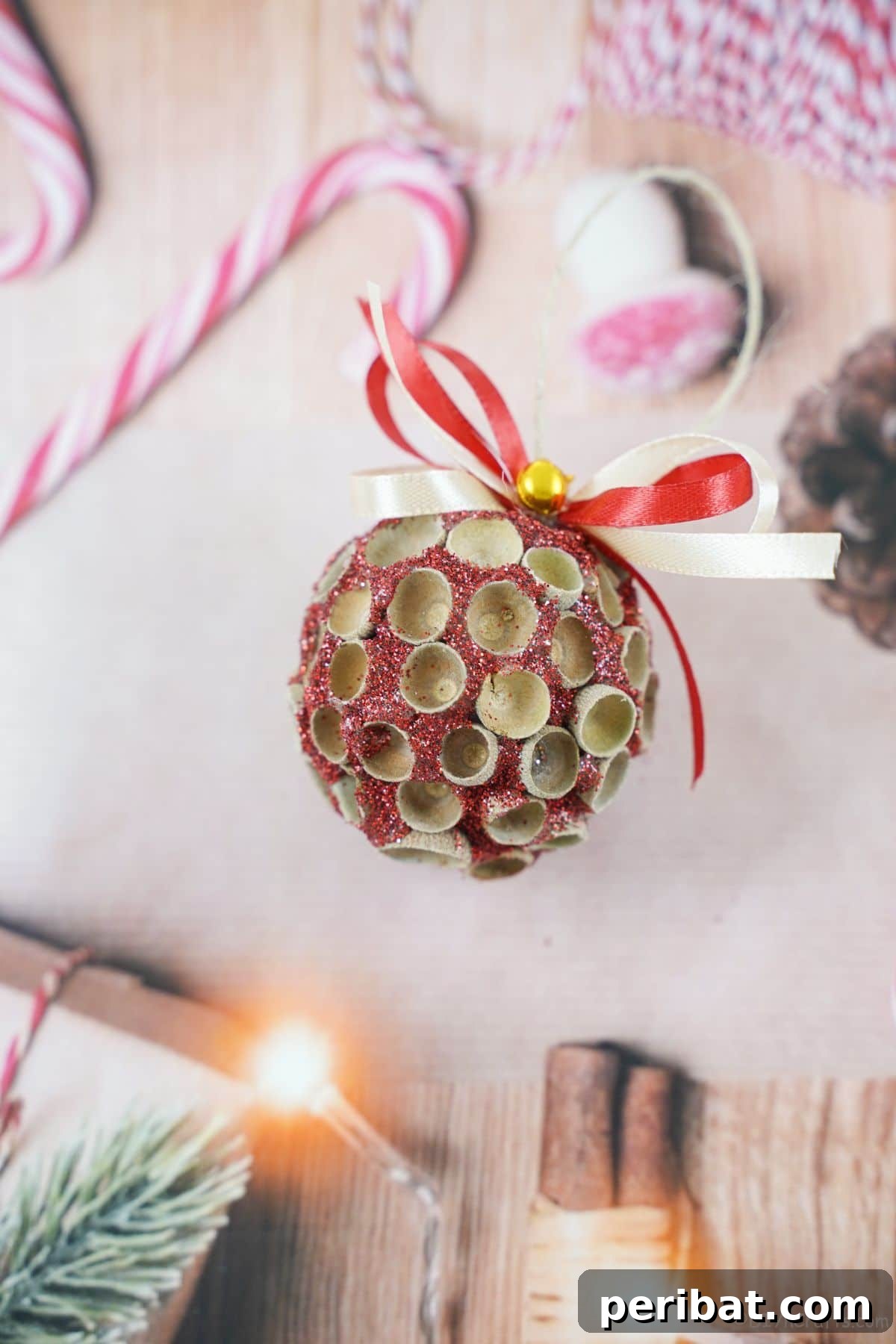 Handcrafted Sparkling Acorn Cap Christmas Ornament 4 A vibrant glitter ornament with meticulously placed acorn caps, set against holiday-themed patterned paper, highlighting its intricate details.