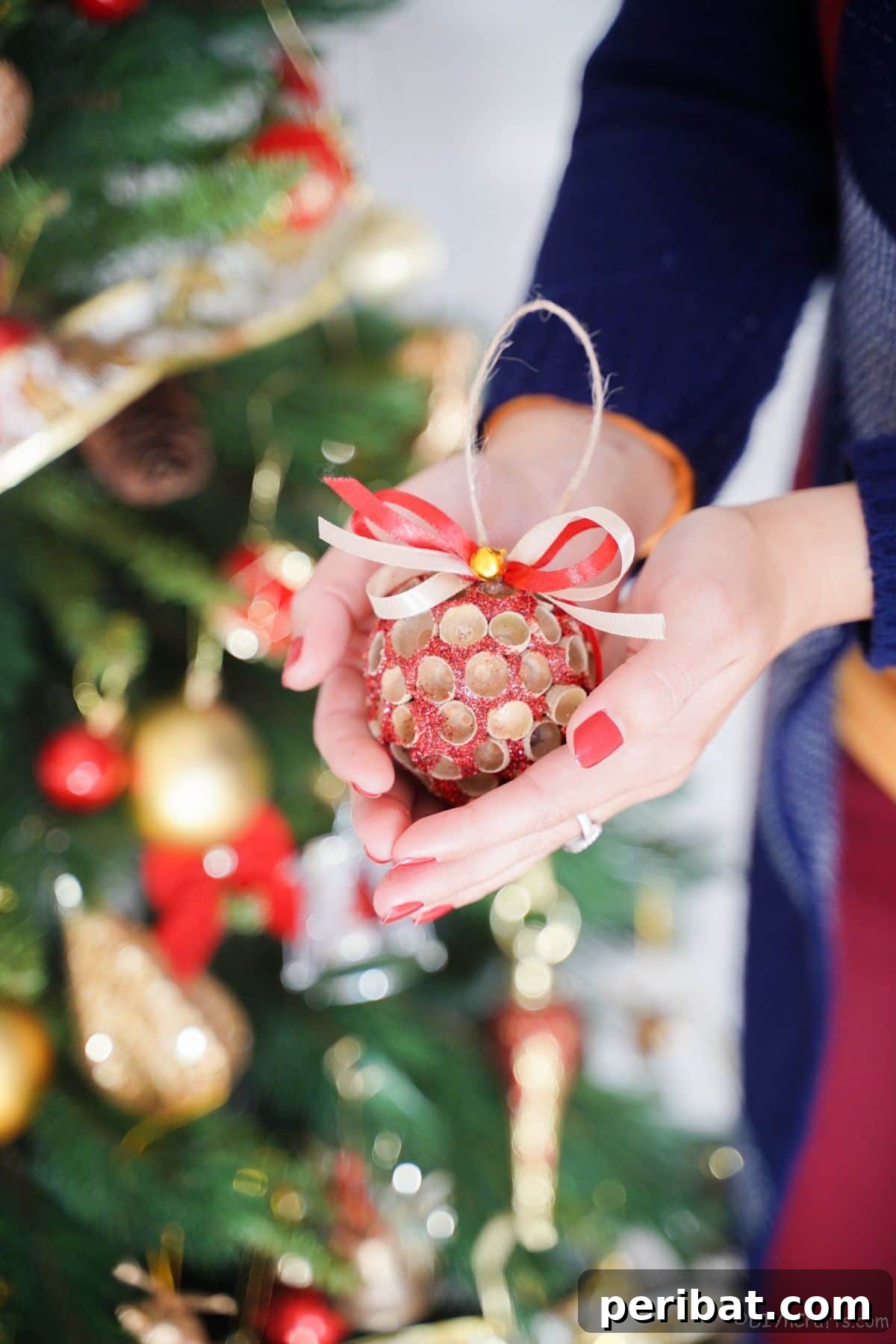 Handcrafted Sparkling Acorn Cap Christmas Ornament 6 A person gently holding a finished glittery acorn cap ornament in their hands, showcasing its handmade beauty and sparkle.
