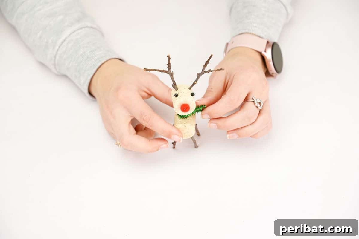 Whimsical Wine Cork Reindeer Ornament 14 hand adding green pipe cleaner scarf to reindeer made of cork