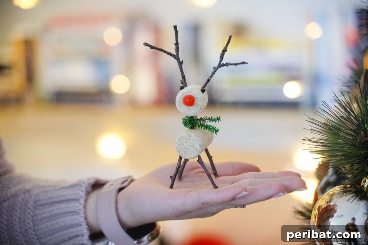 Whimsical Wine Cork Reindeer Ornament 7 A handcrafted wine cork reindeer held gently in a hand, with the soft glow of a decorated Christmas tree blurred in the background, highlighting the homemade charm.