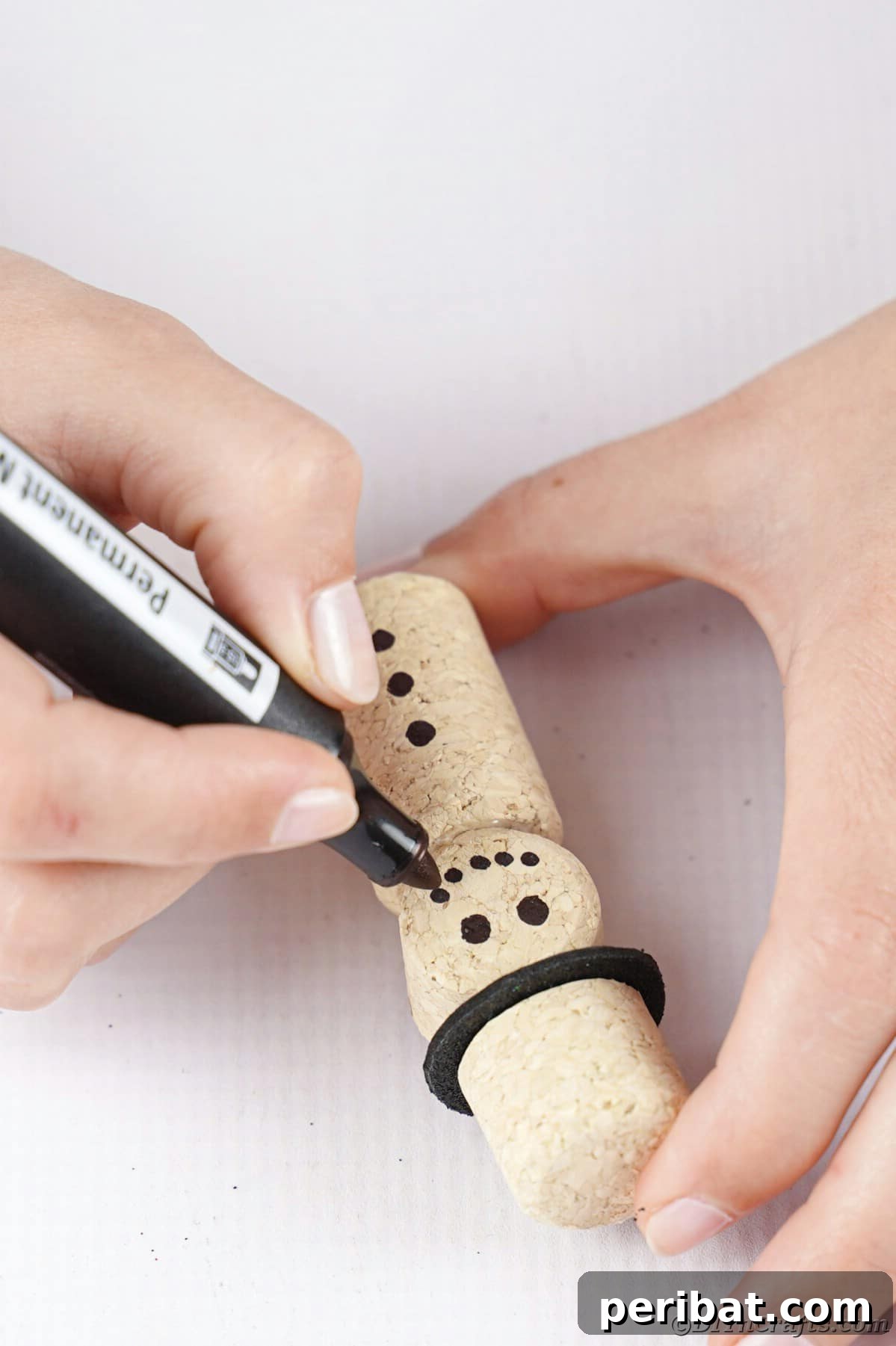 black marker being used to create face on cork snowman