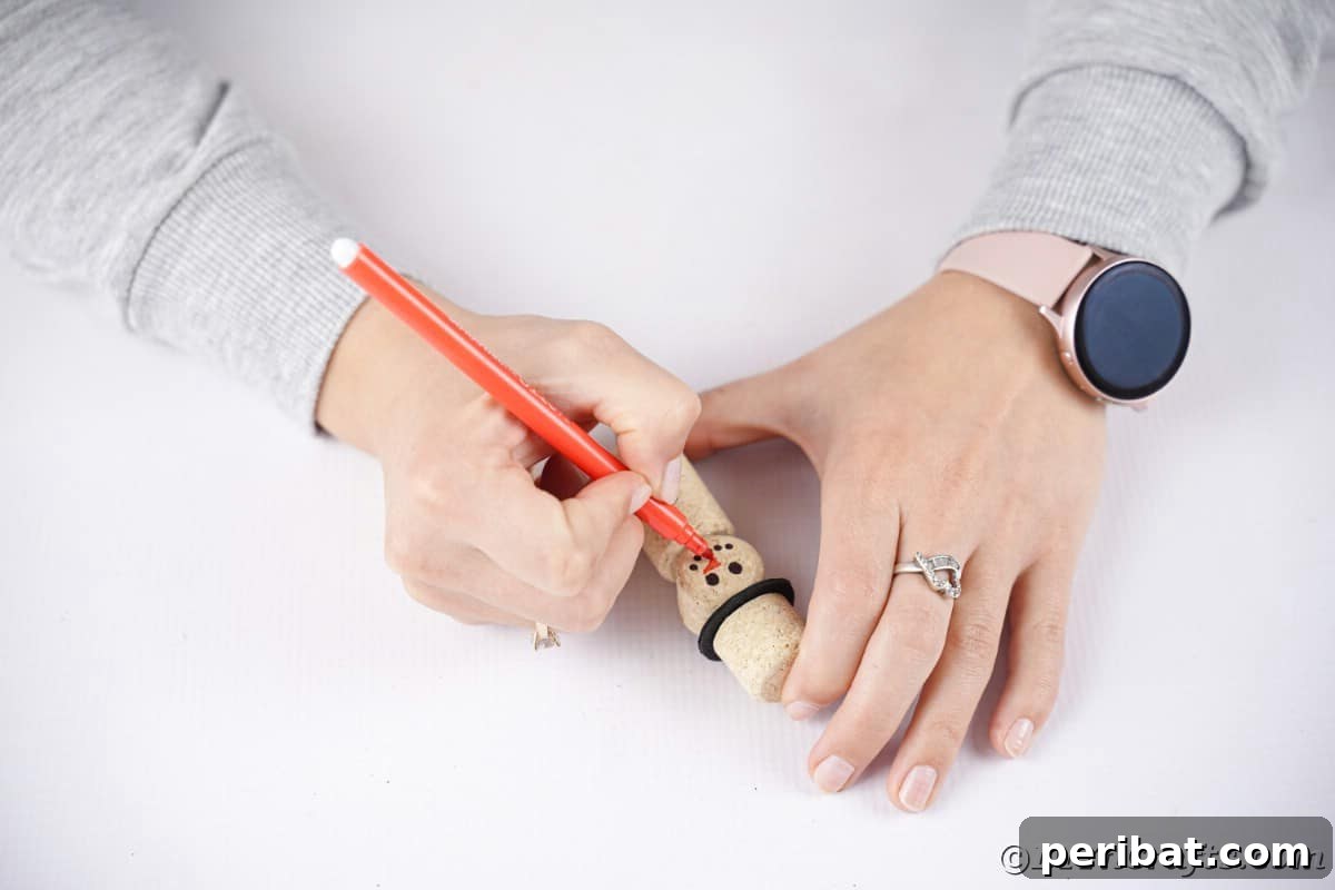orange marker in ladies hand writing on snowman ornament