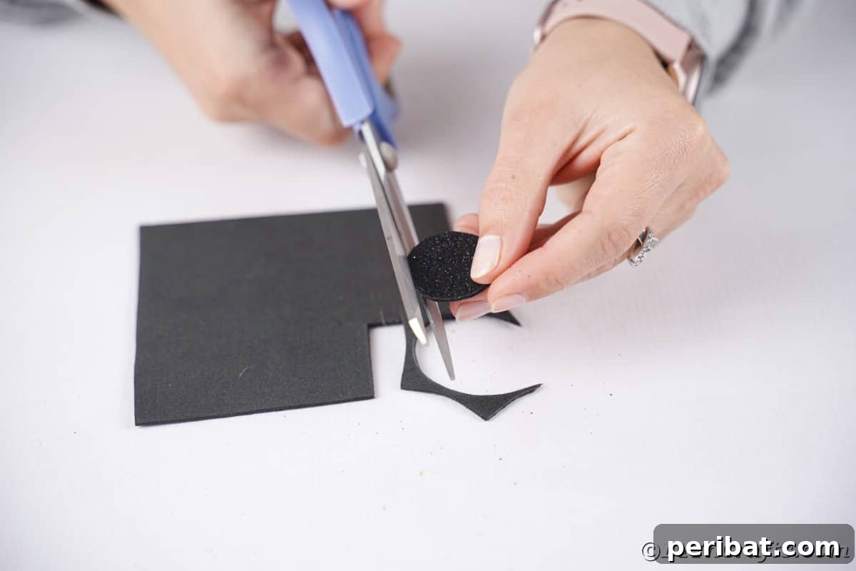 hand using blue scissors to cut circle out of felt