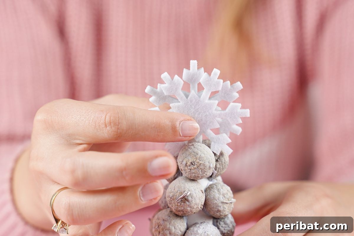Hands holding snowflake on top of acorn cap tree