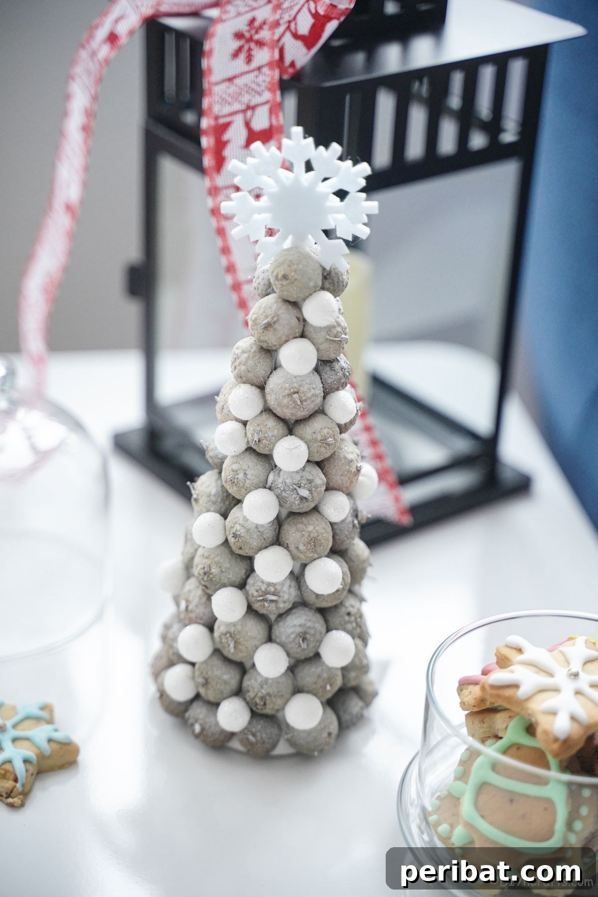 mini christmas tere on white table with black lantern in background