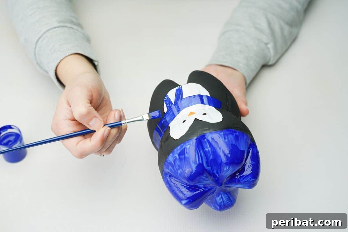 Upcycled Plastic Bottle Penguin Craft for Kids 18 hand painting blue scarf on upcycled bottle penguin