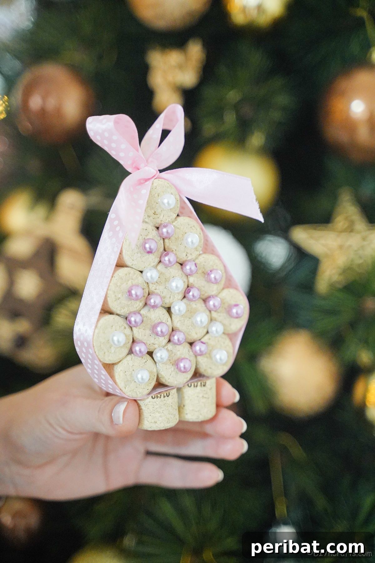 miniature cork tree being held in front of the holiday tree, showcasing the finished DIY project