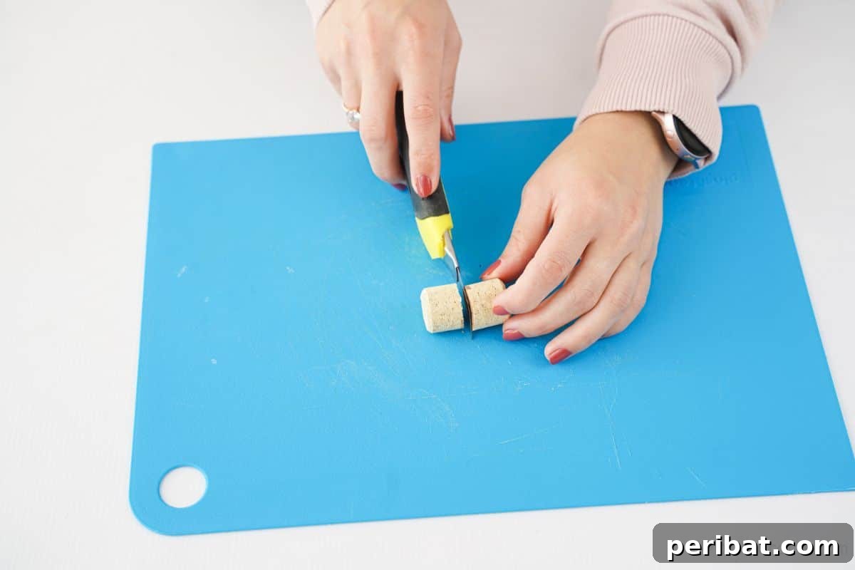 hand cutting cork in half on blue cutting mat, preparing materials for DIY Christmas tree
