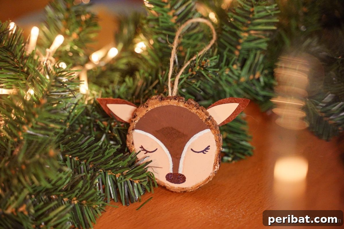 Naturally Charming Reindeer Wood Slice Decor 3 Handmade wood slice reindeer ornament resting on a table beside evergreen garland