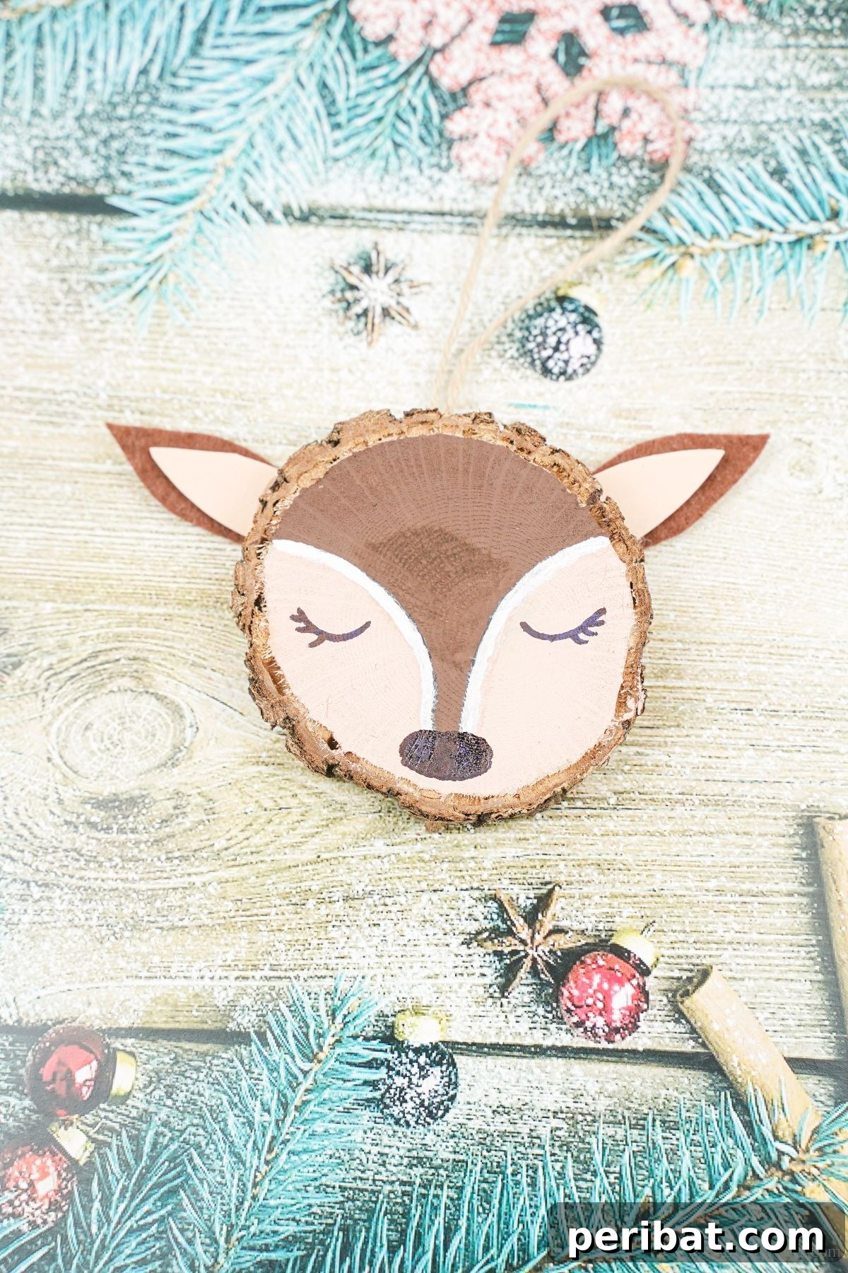 Naturally Charming Reindeer Wood Slice Decor 4 Close-up of a wood slice reindeer ornament with a black nose on blue holiday paper