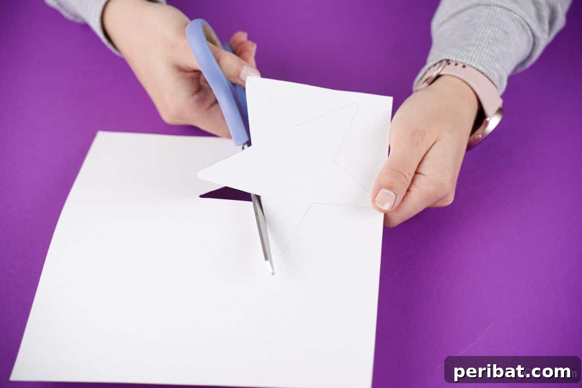 hand holding blue scissors cutting star from paper
