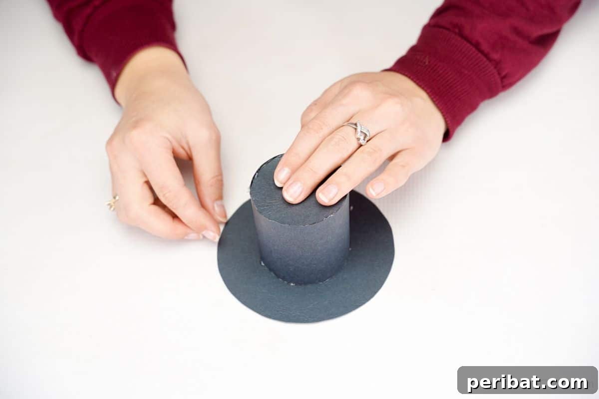 DIY Rustic Wood Slice Snowman Decor 7 A completed black paper hat resting on a clean white table, ready to be added to the wood slice snowman