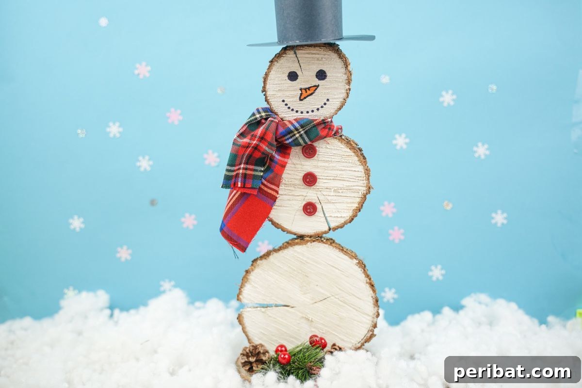 DIY Rustic Wood Slice Snowman Decor 3 Adorable snowman made from painted wood slices, sitting on fake snow against a soft blue background, highlighting its handmade charm