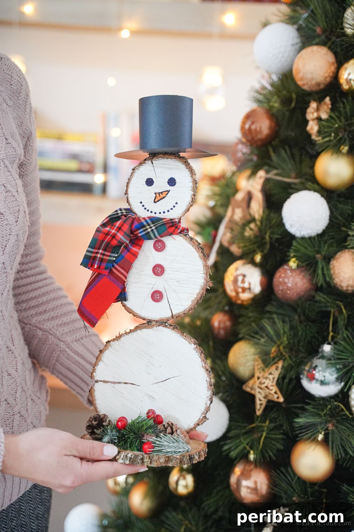DIY Rustic Wood Slice Snowman Decor 17 A lady proudly holding her finished wood slice snowman in front of a beautifully decorated Christmas tree, ready for display