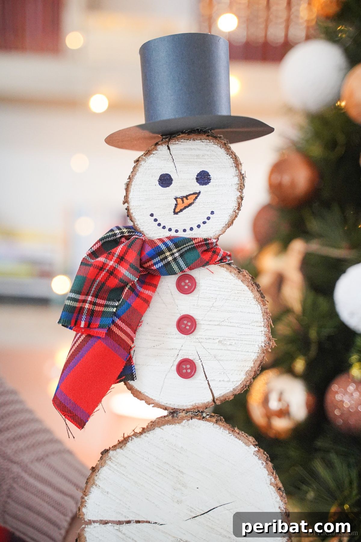 DIY Rustic Wood Slice Snowman Decor 18 A charming wooden slice snowman proudly standing in front of a holiday tree, showcasing its rustic beauty and handmade appeal